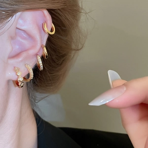 Primo piano di una donna che indossa cerchi placcati in oro e borchie di zirconi in macro