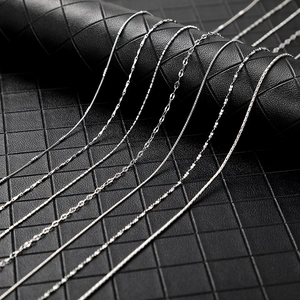 Detail of assorted silver metal chain styles including box and snake chains on leather