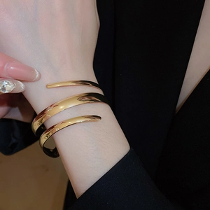 Detailed view of wide gold spiral wrap bracelet with high-polish metallic finish