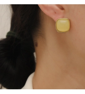 Close-up of minimalist square yellow resin earring with gold metal trim on model