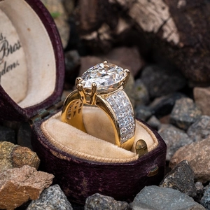 Macro detail of pear-cut zircon gold ring with pavé diamonds in a vintage velvet gift box