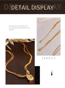 Detail view of double-layer gold snake chain necklace with heart stone pendant