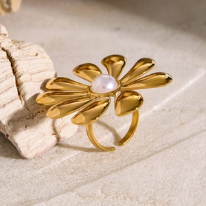Artistic close-up of a gold sunflower ring with pearl center on stone background