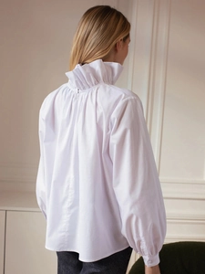 Detail of white long sleeve shirt showing elegant ruffled high neck and back zipper closure