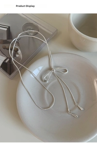 Dettaglio della collana a fiocco argento con pendenti a goccia su un piatto di porcellana