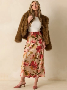 Detail of brown faux fur jacket paired with a floral silk midi skirt and white top