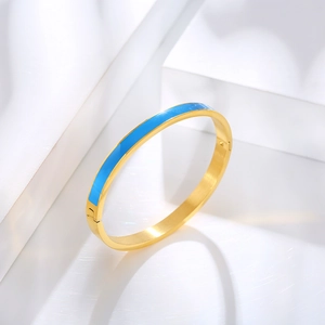 Close-up of gold hinged bangle featuring blue enamel inlay on polished stainless steel