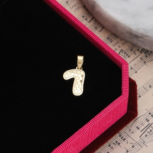 Close-up of golden number 7 pendant with dot texture in a luxury black velvet box