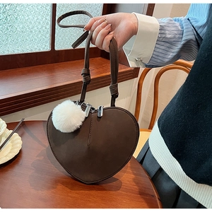 Detail der dunkelbraunen Herz-Handtasche mit weißem Kunstfell-Anhänger und Doppelreißverschluss