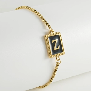 Macro detail of gold adjustable bracelet with Z initial black enamel pendant