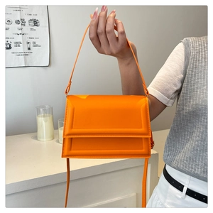 Detail view of orange PU leather crossbody bag with geometric embossed lines and handle