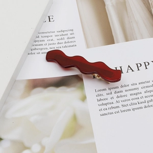 Burgundy acetate wavy hair clip with gold metal base on elegant white background card