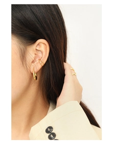 Detail showing gold teardrop earring and double-layered ear cuff worn by a model