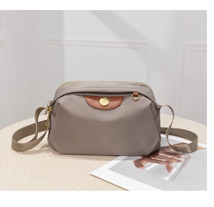 Detail of grey oxford crossbody bag with brown leather trim and golden hardware accents