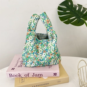 Detailed texture of corduroy floral wrist bag placed on books with tropical leaf decor