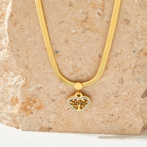 Detail of gold snake chain necklace featuring a heart-shaped tree of life pendant with crystals