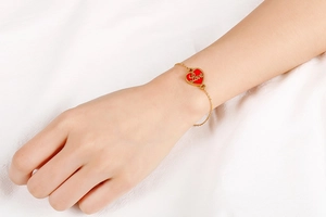 Close-up of a gold stainless steel bracelet featuring a red heart pendant with Love engraving