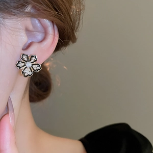 Detailed close-up of a vintage black and gold flower earring with a central pearl inlay