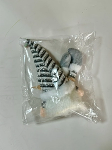 Close-up of a glowing Christmas gnome in silver striped hat and clear plastic packaging