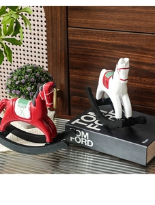 Détail de figurines de chevaux à bascule en bois peints en rouge et blanc sur étagère