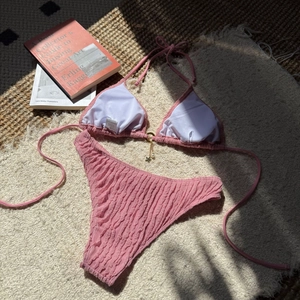 Close-up of pink textured bikini top with star pendant and soft lighting on rug