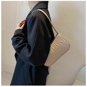 Detail view of the beige textured underarm bag showing the stylish pleated PU leather surface