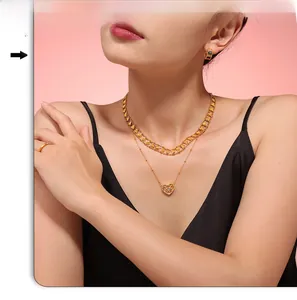 Detail of layered gold heart necklace and jewelry set worn by a model in black dress