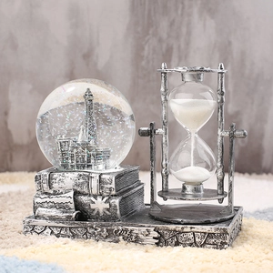 Close-up of vintage Eiffel Tower crystal ball and hourglass on a stack of books base