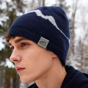 Winter navy knit beanie with white mountain pattern and leather patch in snow setting