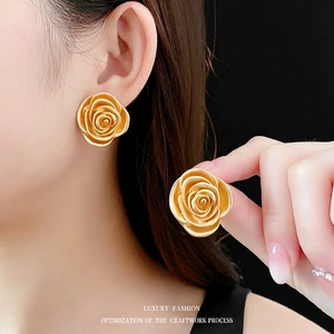 Vintage matte gold rose flower stud earrings shown on ear for realistic scale