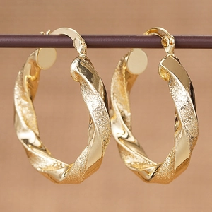 Makro-Detail von schicken goldenen gedrehten Creolen mit polierten und mattierten Texturen