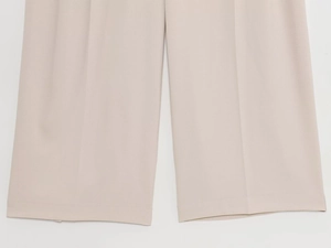 Vue macro détaillée du pantalon large beige montrant le tissu tissé et les coutures soignées