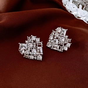 Macro shot of zircon crystal heart studs on dark satin fabric with light reflections