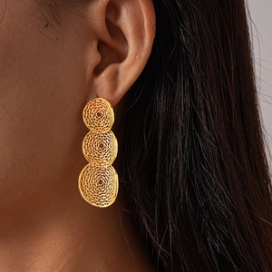 Detail of gold hollow mesh geometric circular earrings worn as a trendy earring accessory