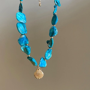Halsketting met blauwe schelpkralen en gouden sint-jakobsschelp hanger in strandstijl
