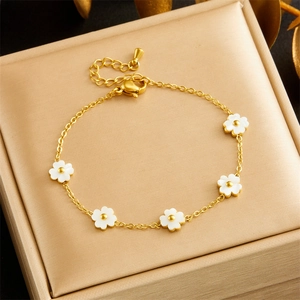 Elegant gold flower chain bracelet with white petals displayed in a beige jewelry box