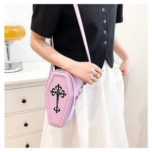 Close-up of a lavender coffin-shaped crossbody bag with a black gothic cross detail