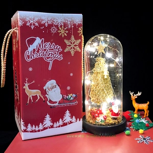 Detail of Christmas tree glass dome with reindeer figurine and red festive gift box