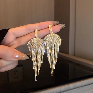 Detail view of shimmering crystal leaf tassel earrings with long metallic fringe design
