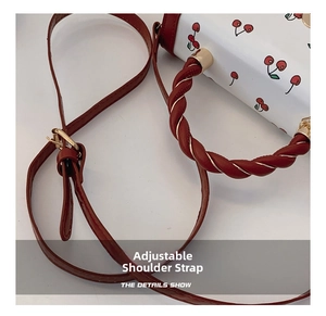 Detail of adjustable burgundy strap and twisted rope handle on cherry print small square bag