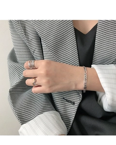 Detail of elegant silver wavy ring and link bracelet on model wearing houndstooth blazer