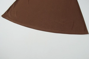 Détail de l'ourlet de robe en tricot marron foncé avec texture fine et couture lisse