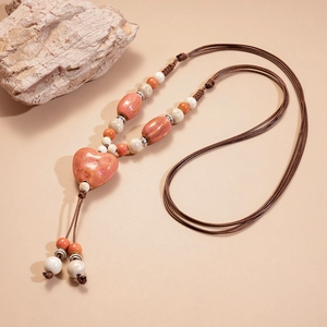 Détail du collier pendentif cœur en céramique rose avec cordon tressé marron