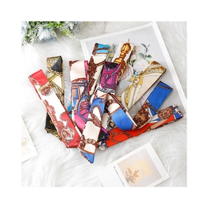 Elegant assortment of patterned silk skinny scarves displayed on white plush fabric