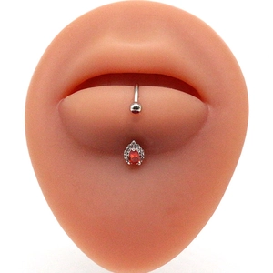 Detail of silver curved barbell with red teardrop gem and pavé crystals on silicone model
