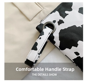 Detail of PU leather cow print clutch showing the comfortable wrist strap and metal eyelet
