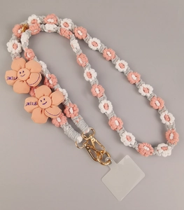 Detail of pink and white hand-woven floral phone strap with Smile embroidery and gold clasp