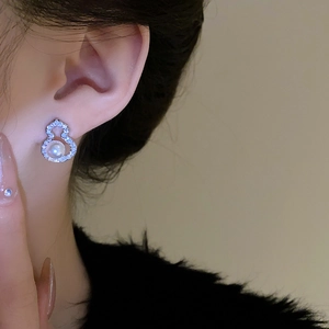 Close-up of silver gourd earring with small diamonds and a center pearl on model