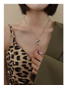 Detailed close-up of a silver dolphin pendant necklace worn with a stylish blazer