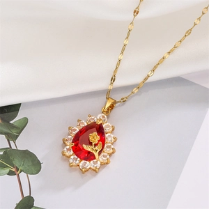 Detail of red teardrop gemstone pendant with gold rose accent on white silk background